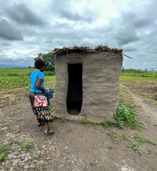 A person entering a small, earthen well house