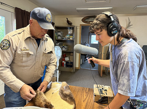 Klara Goldman holding audio-recording equipment and interviewing a Colorado Parks and Wildlife staff member