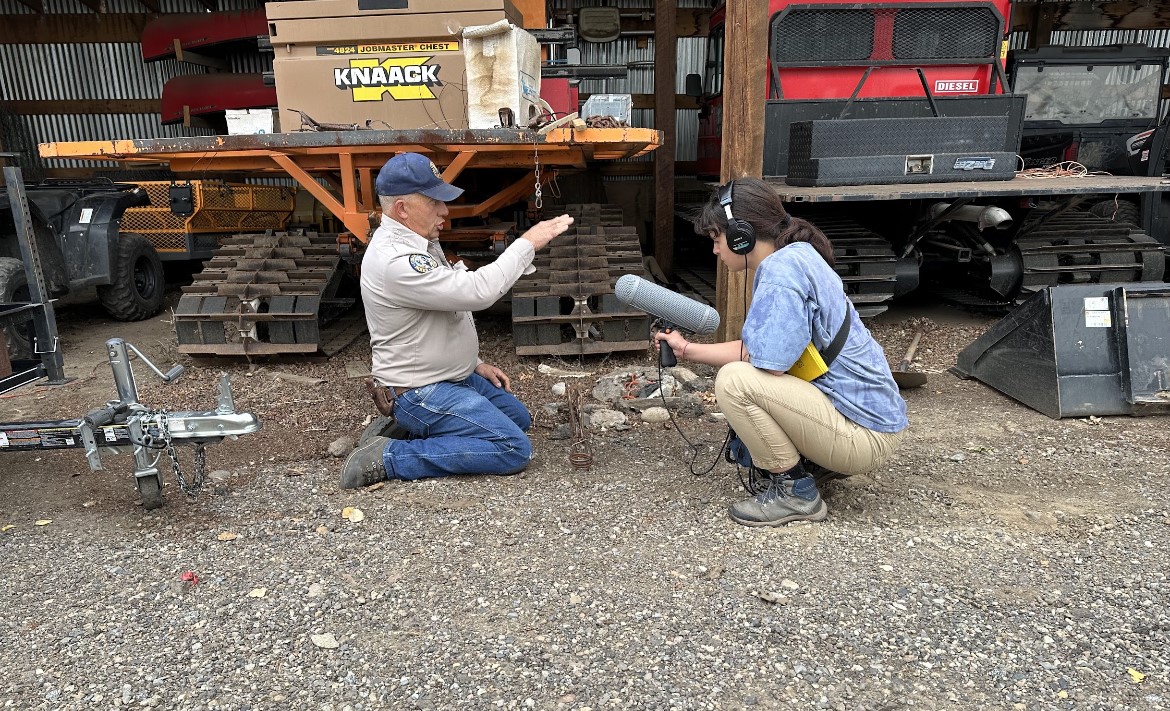 Klara Goldman interviewing a Colorado Parks and Wildlife staff member outside on a gravel lot